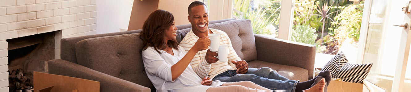 A couple drinking coffee on their sofa